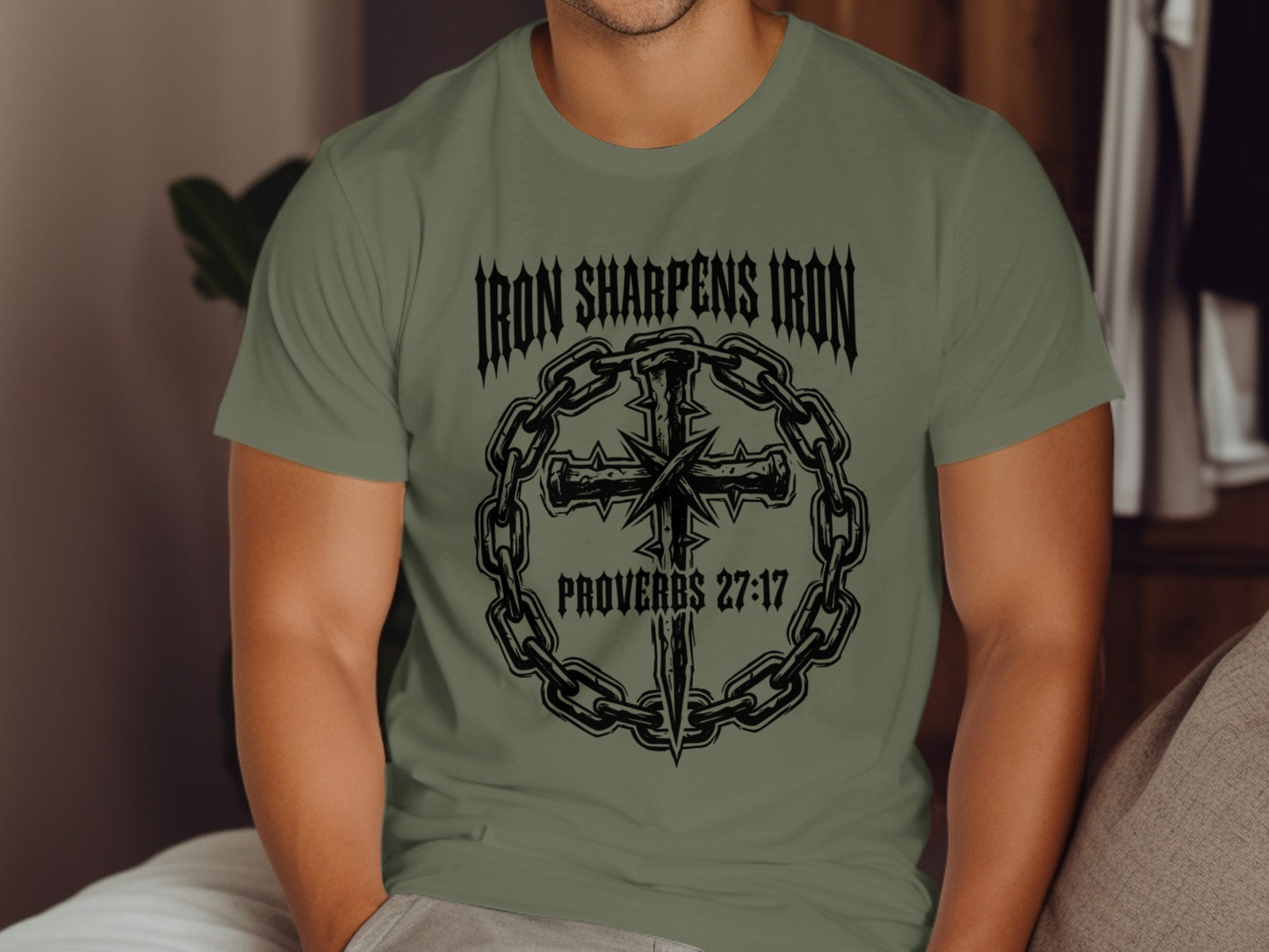 Olive green t-shirt with "Iron Sharpens Iron Proverbs 27:17" and a cross made of chains.