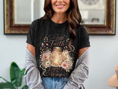 Black t-shirt with "A Little Faith Lights the Way" text and a glowing mason jar.