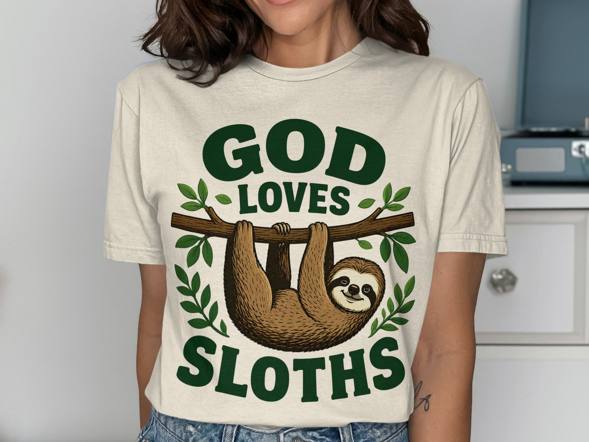Cream t-shirt with "GOD LOVES SLOTHS" and a sloth on a branch.
