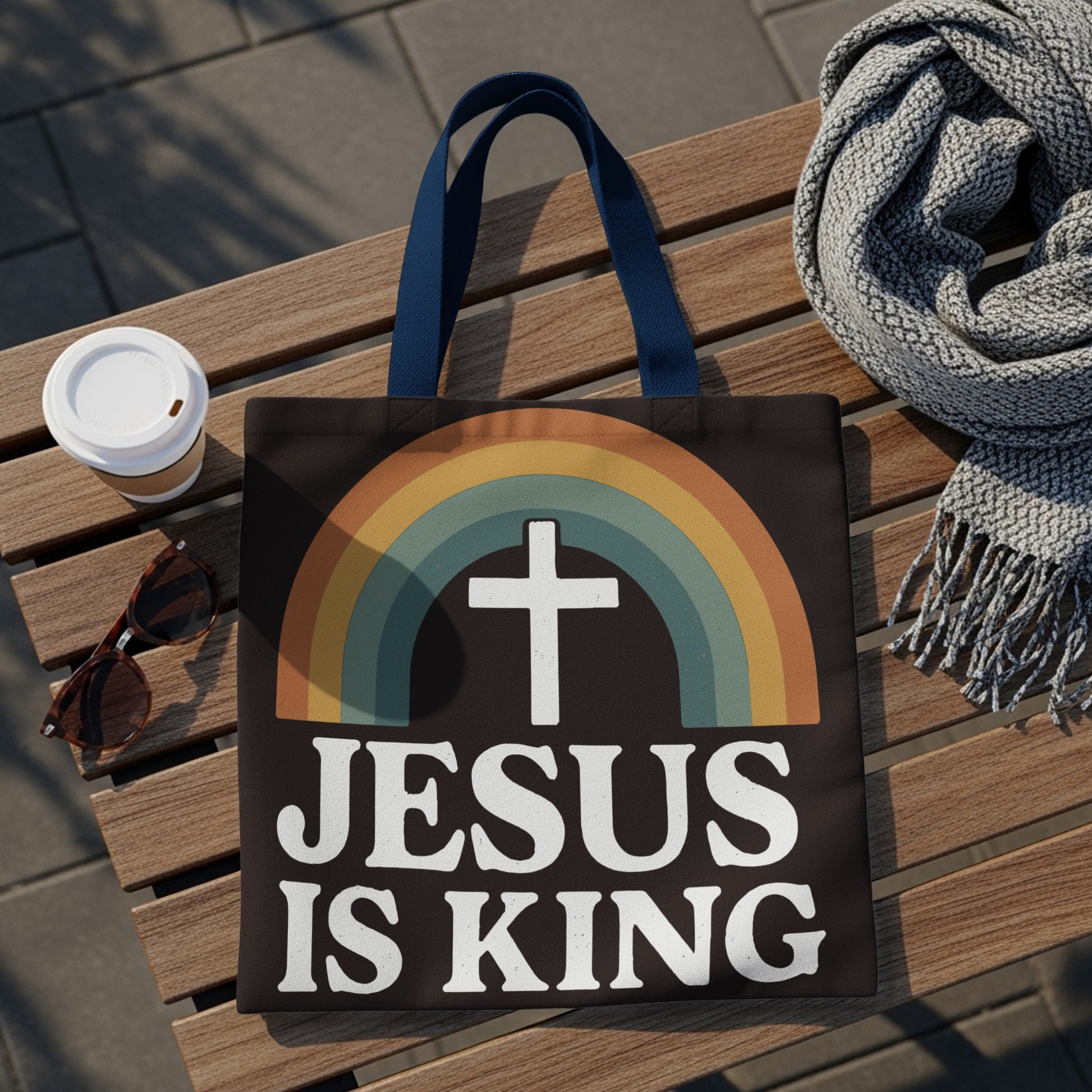 Black tote bag with white "Jesus Is King" text and a retro rainbow with a cross.