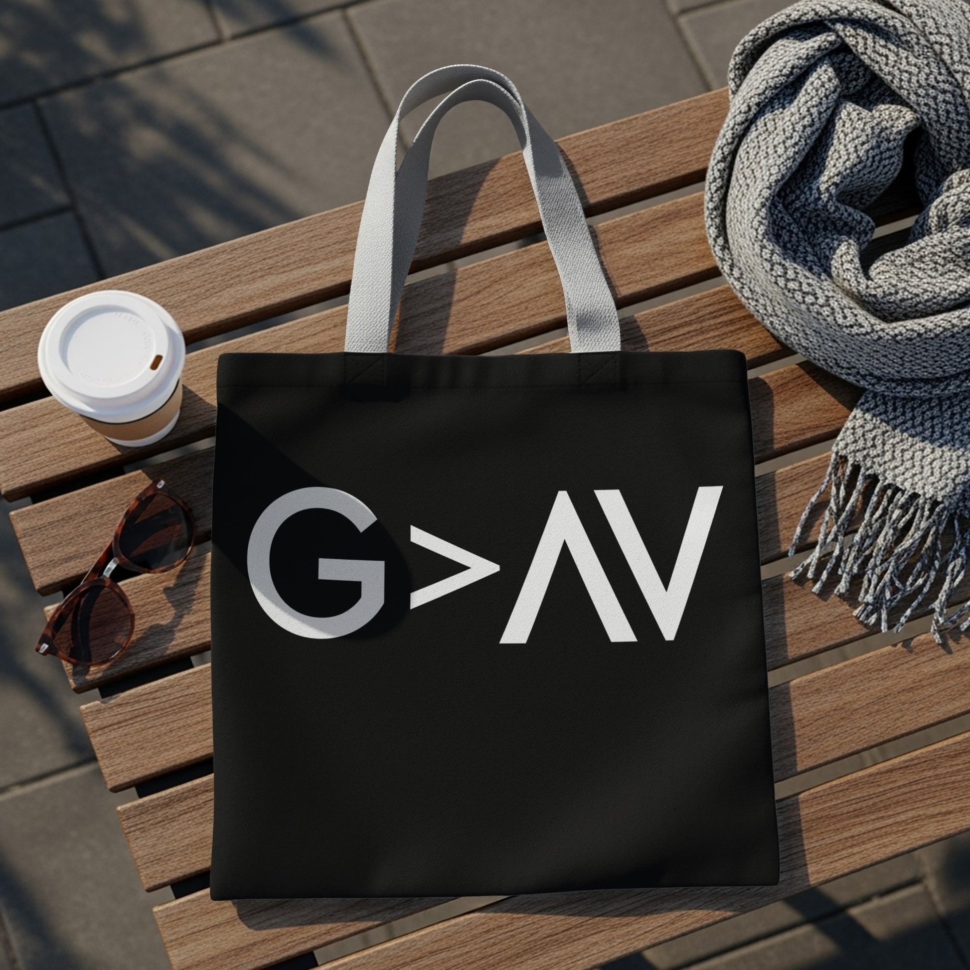 Black tote bag with white "G>AV" text on a wooden bench.