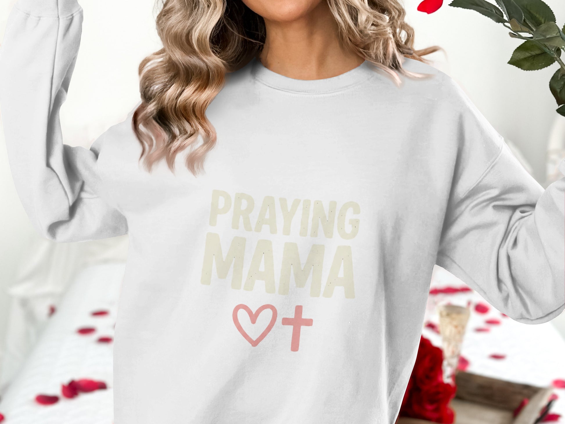White sweatshirt with "Praying Mama" and a pink cross heart.