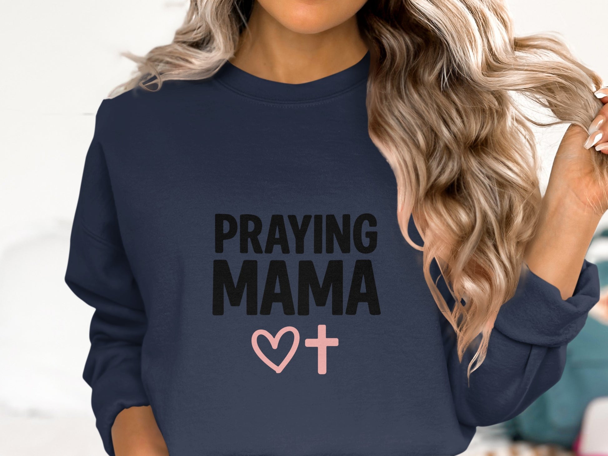 Navy sweatshirt with "PRAYING MAMA" and a pink cross heart graphic.
