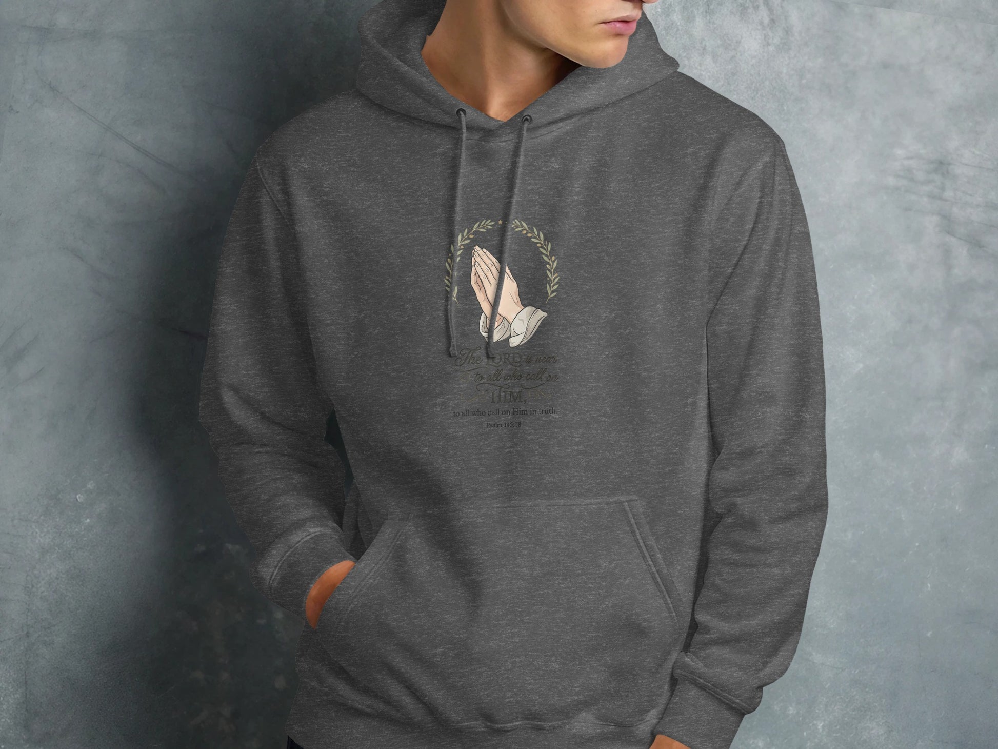 Dark grey hoodie with floral wreath and prayer hands, featuring Bible verse.