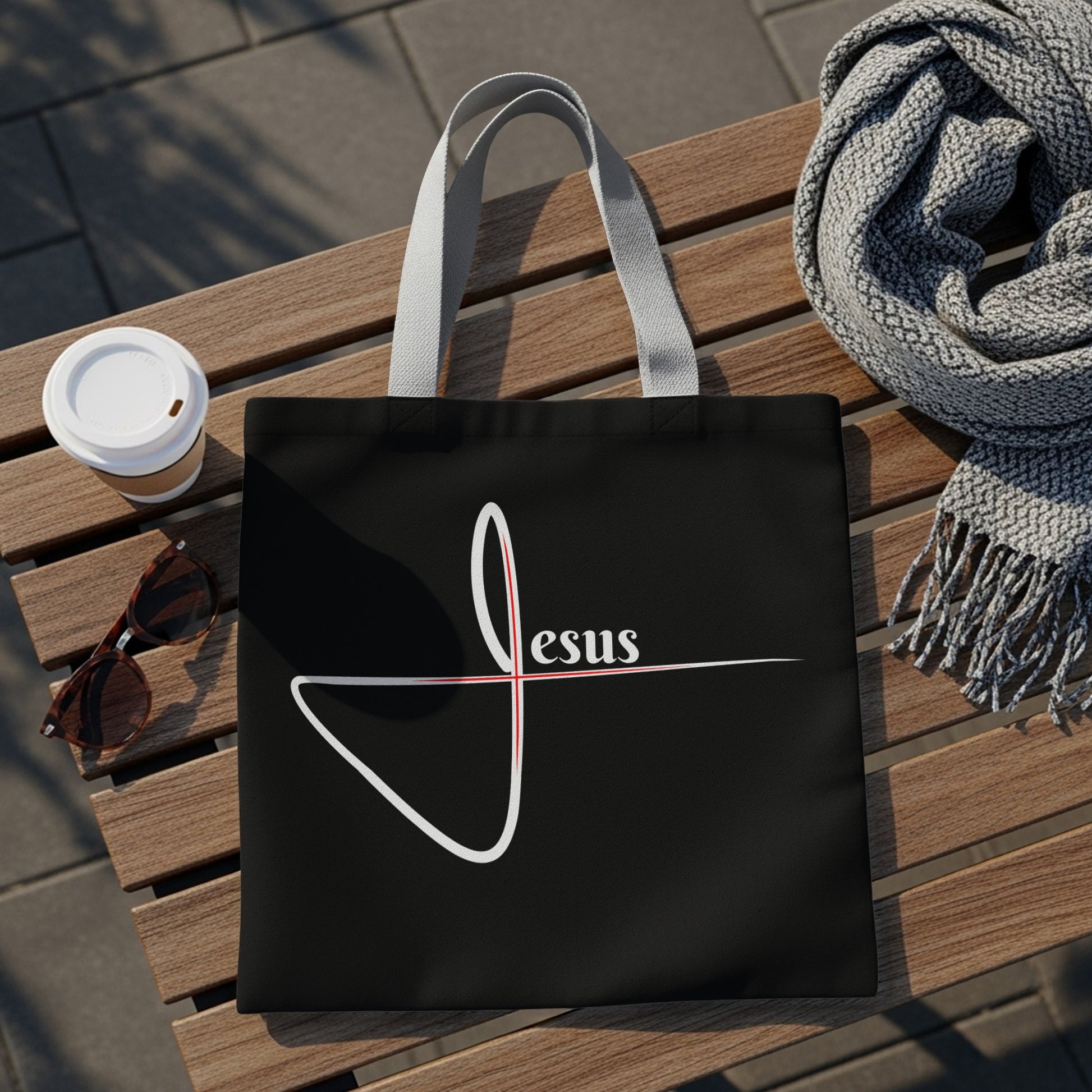 Black tote bag with white and red "Jesus" text and Christian cross design.