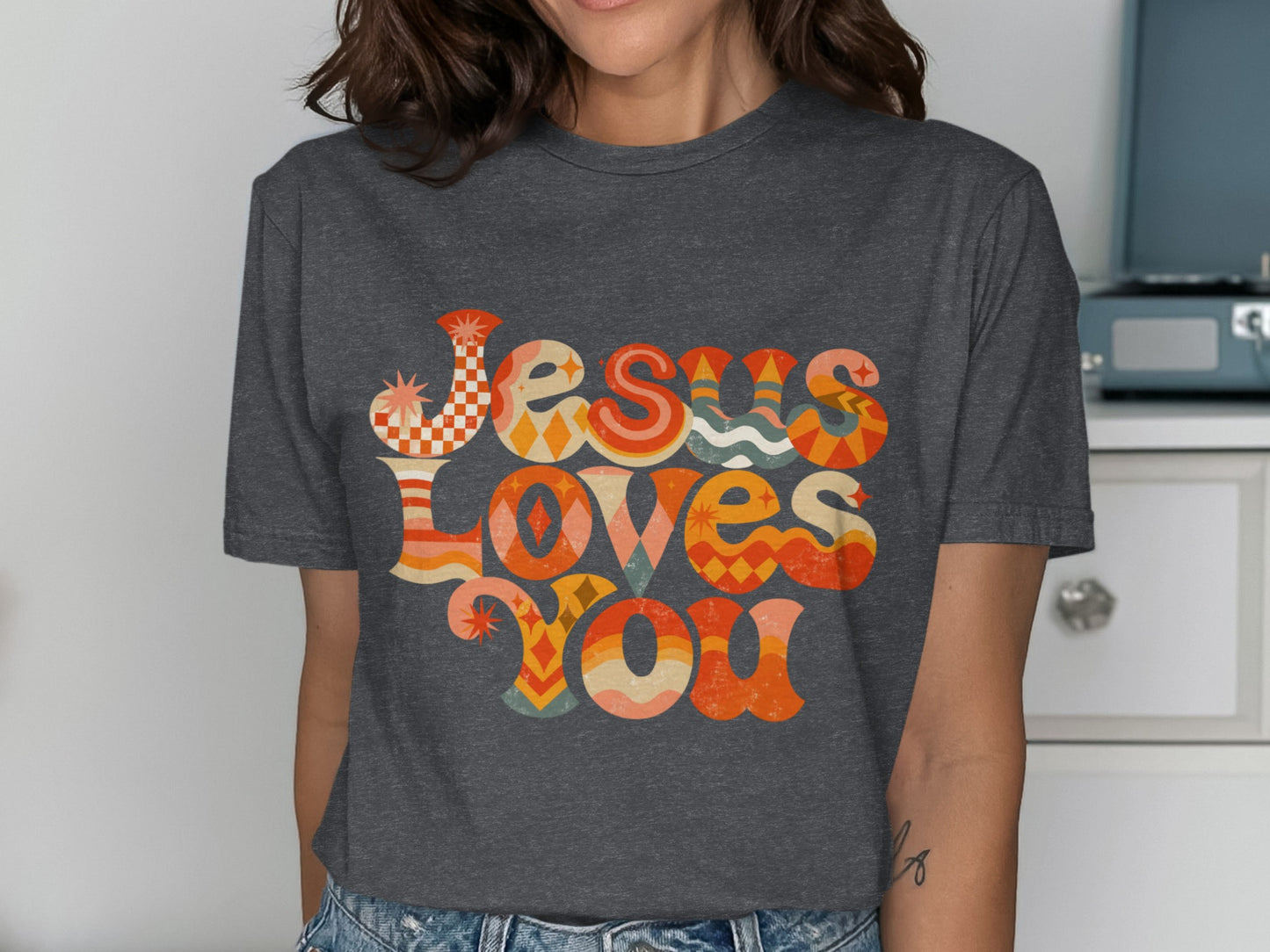 Grey t-shirt with "Jesus Loves You" in colorful retro text.