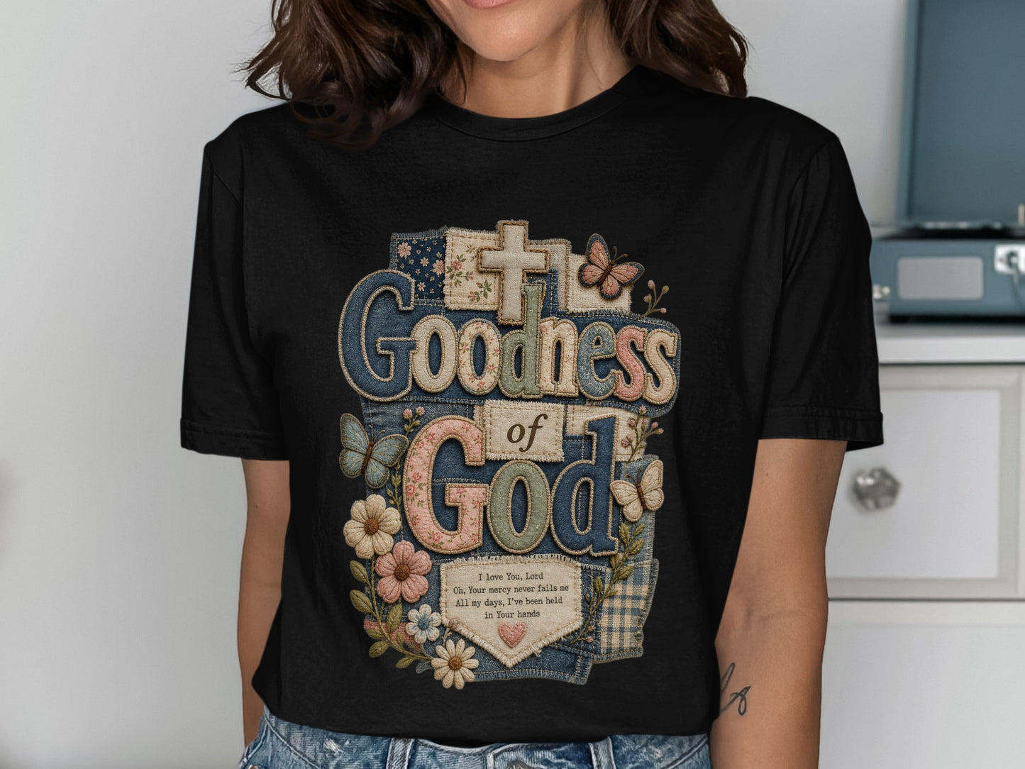 Black t-shirt with "Goodness of God" text and floral butterfly patches.
