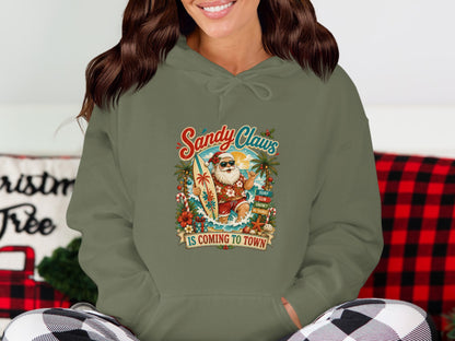 Green hoodie with "Sandy Claws is Coming to Town" and surfing Santa graphic.