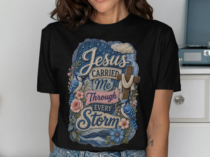 Black t-shirt with "Jesus Carried Me Through Every Storm" text and floral design.