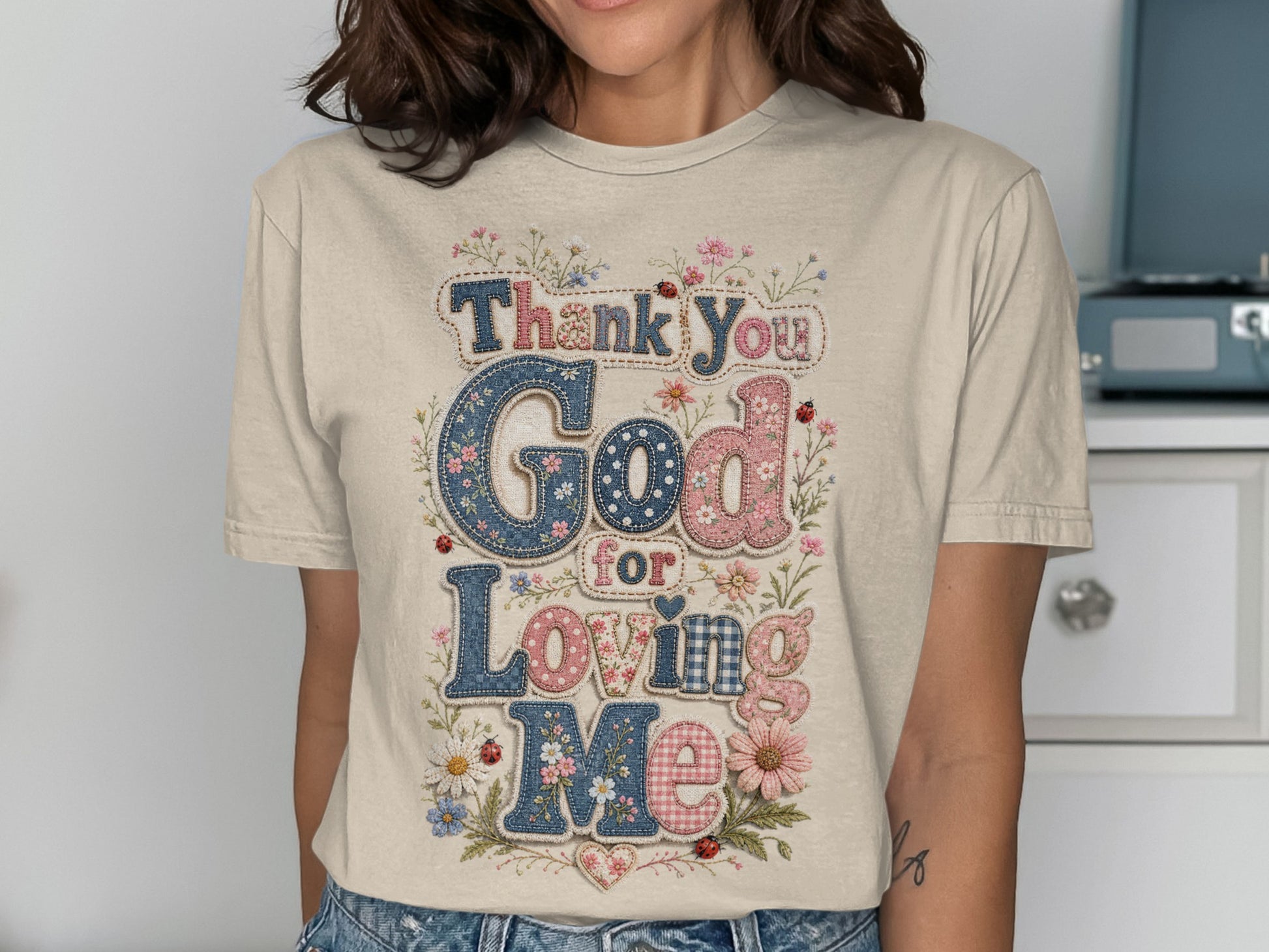 God for Loving Me text on a t-shirt with floral and plaid patterns.