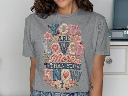 Gray t-shirt with "YOU ARE LOVED MORE THAN YOU KNOW" text in patchwork font.