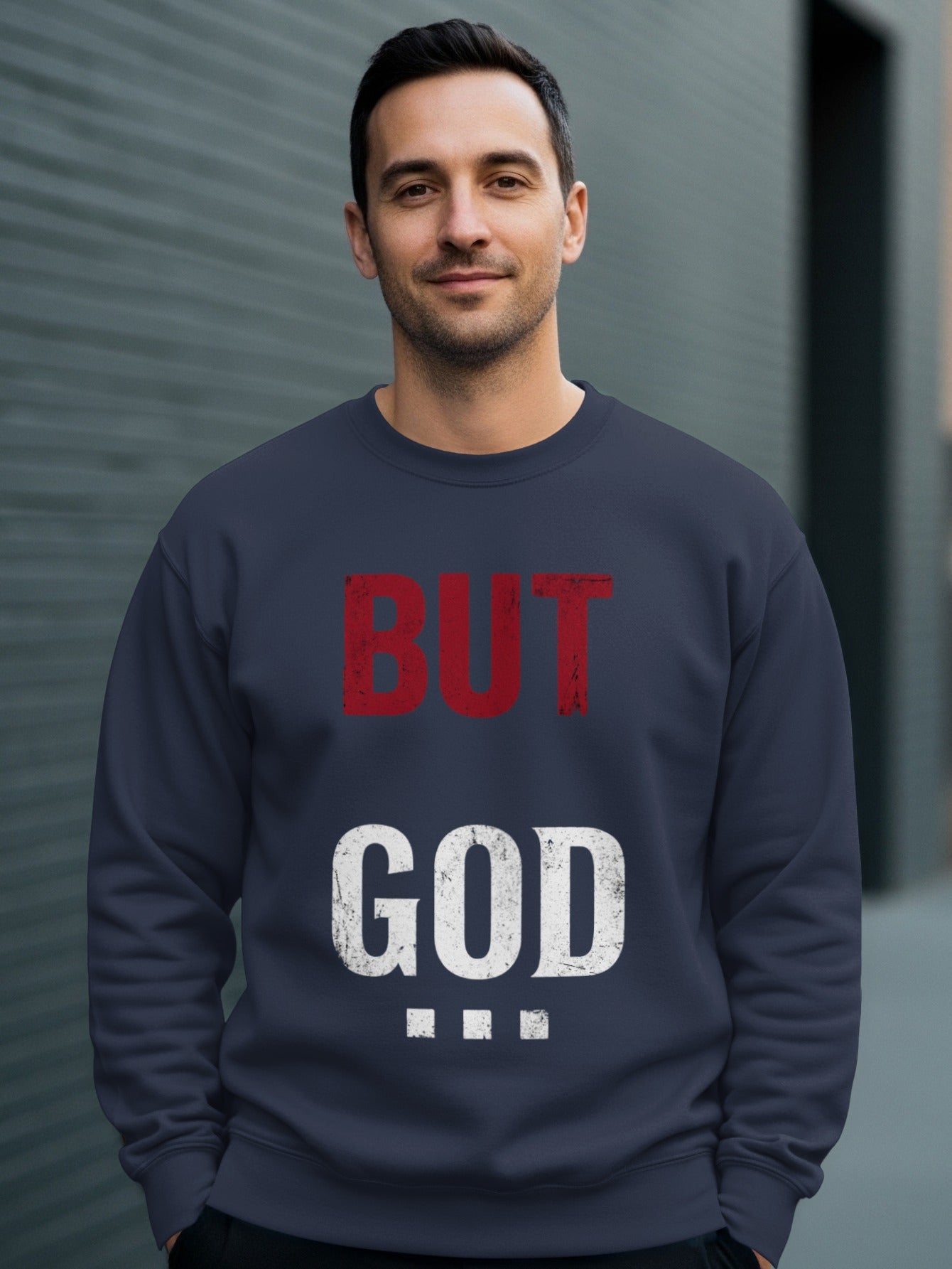 Navy sweatshirt with "BUT GOD" and three dots in red and white text.