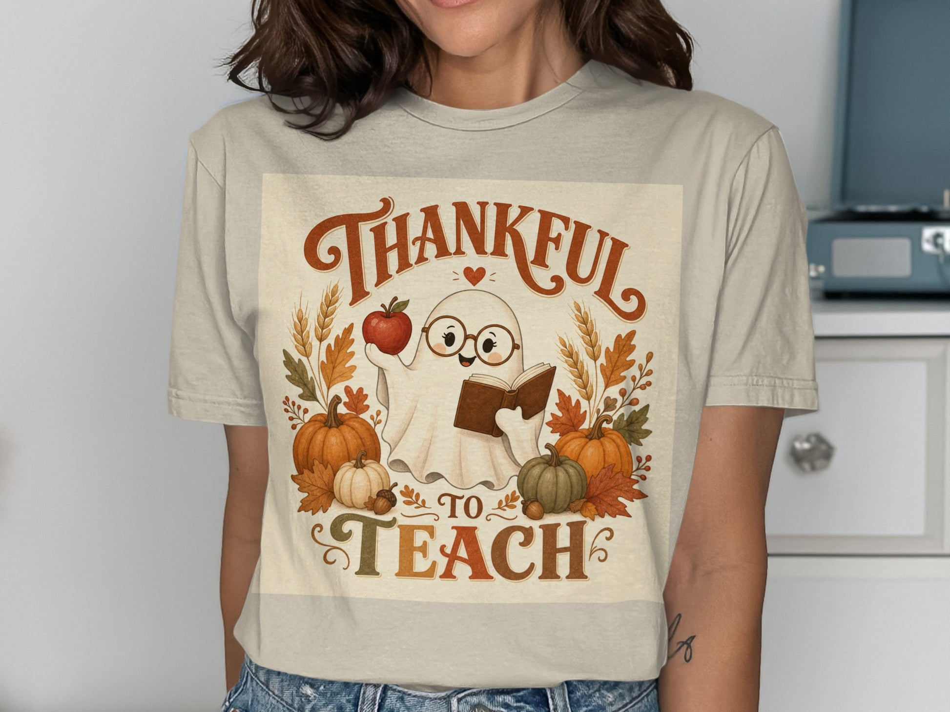 Ghost character holding book and apple, text "Thankful to Teach", pumpkins, and fall leaves.
