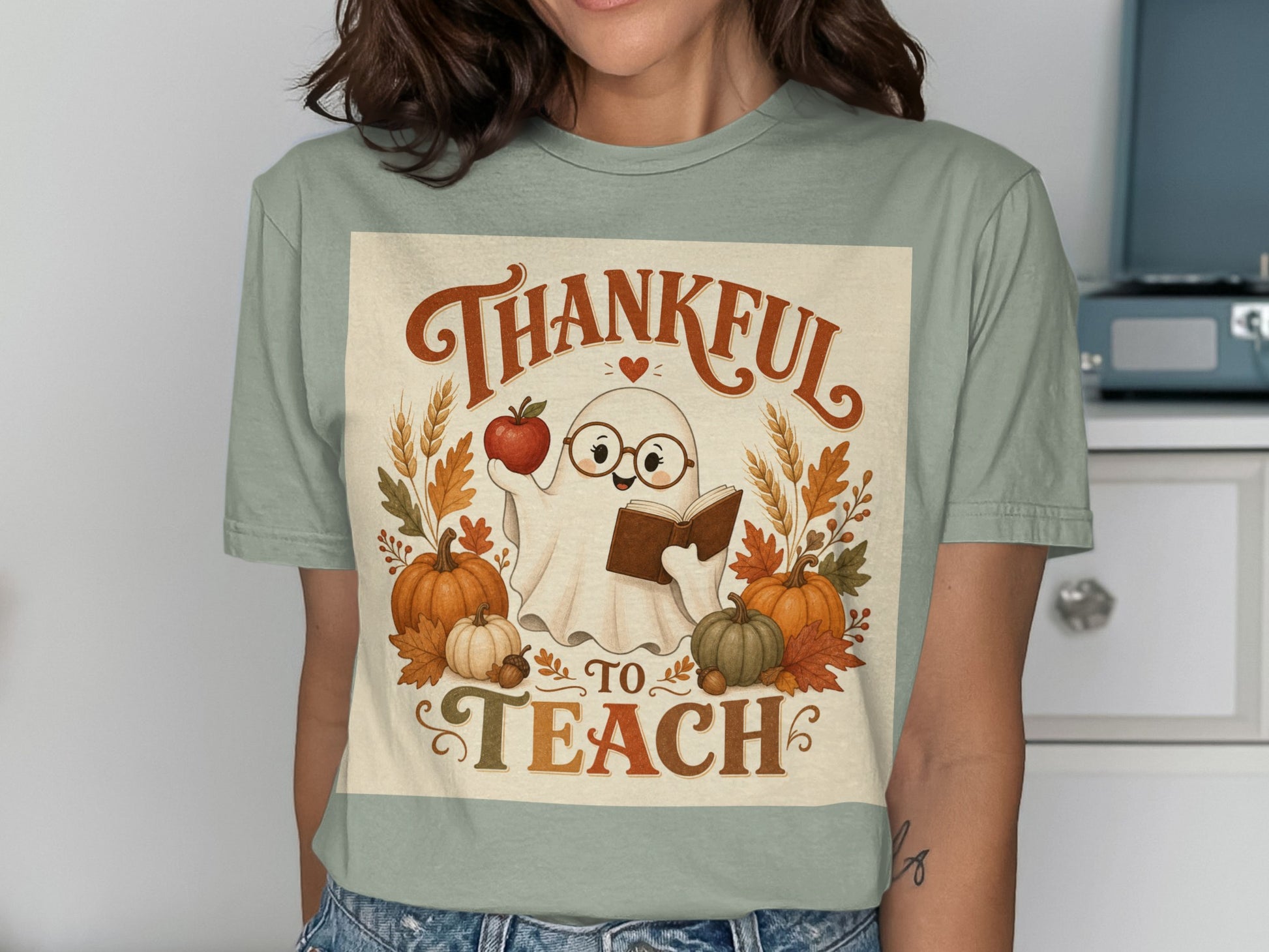 Cute ghost in glasses holding an apple and book with pumpkins and leaves, "Thankful to Teach" text.