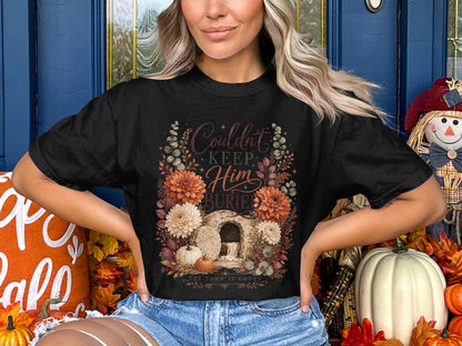 Black t-shirt with floral design of tomb and text "Couldn't Keep Him Buried, The Tomb is Empty."