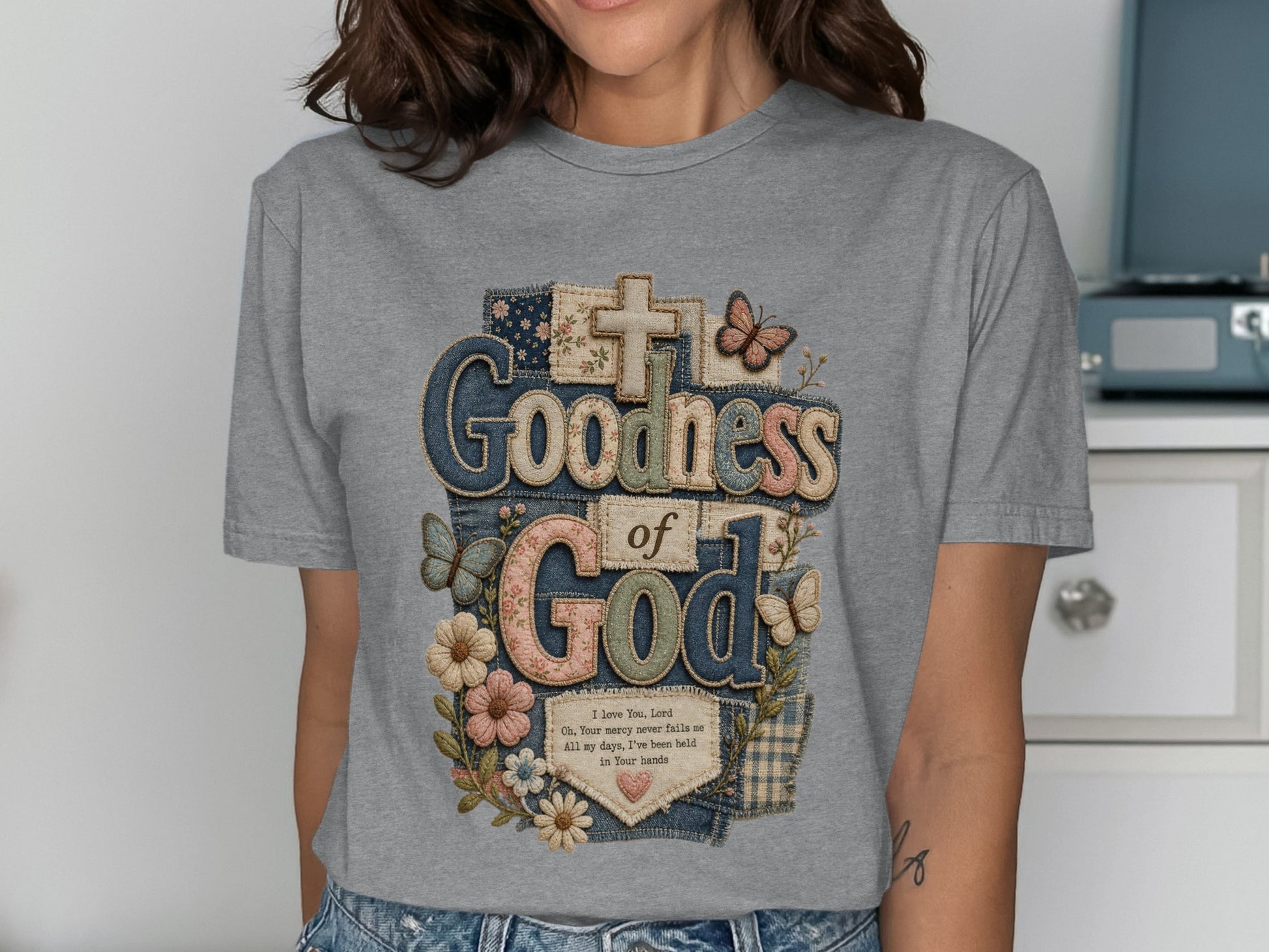 T-shirt with "Goodness of God" text, floral, butterfly, and cross design.