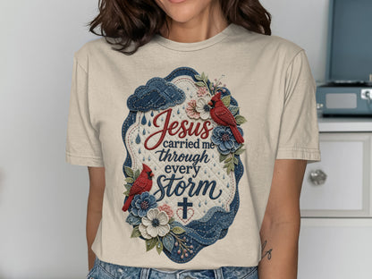T-shirt with "Jesus carried me through every storm" text and floral, cloud, and cross design.