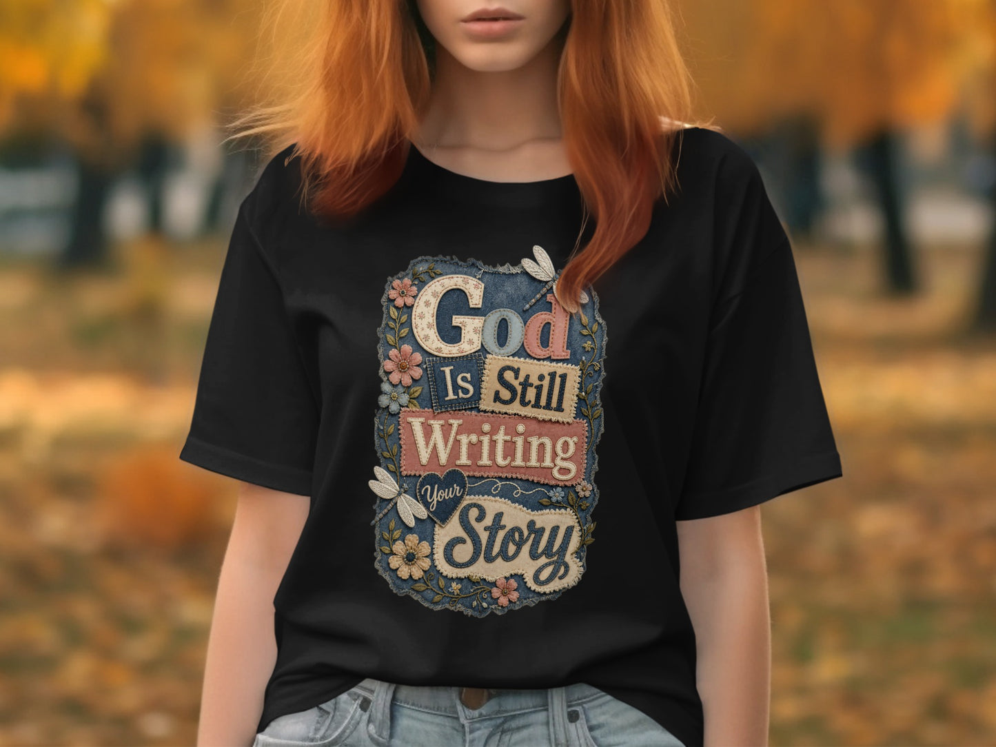 Black t-shirt with "God Is Still Writing Your Story" text and floral accents.
