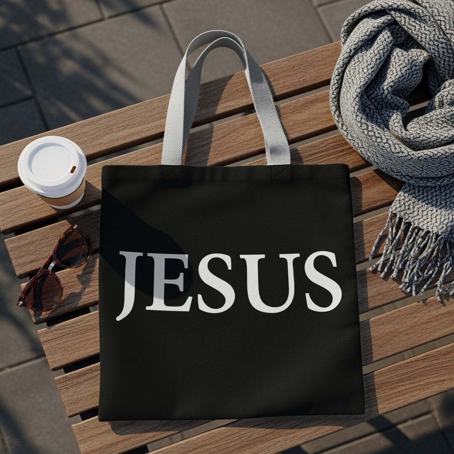 Black tote bag with "JESUS" printed in white text.