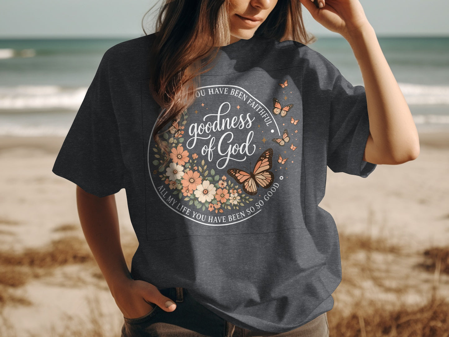 Dark t-shirt with floral wreath and butterflies, "Goodness of God" text.