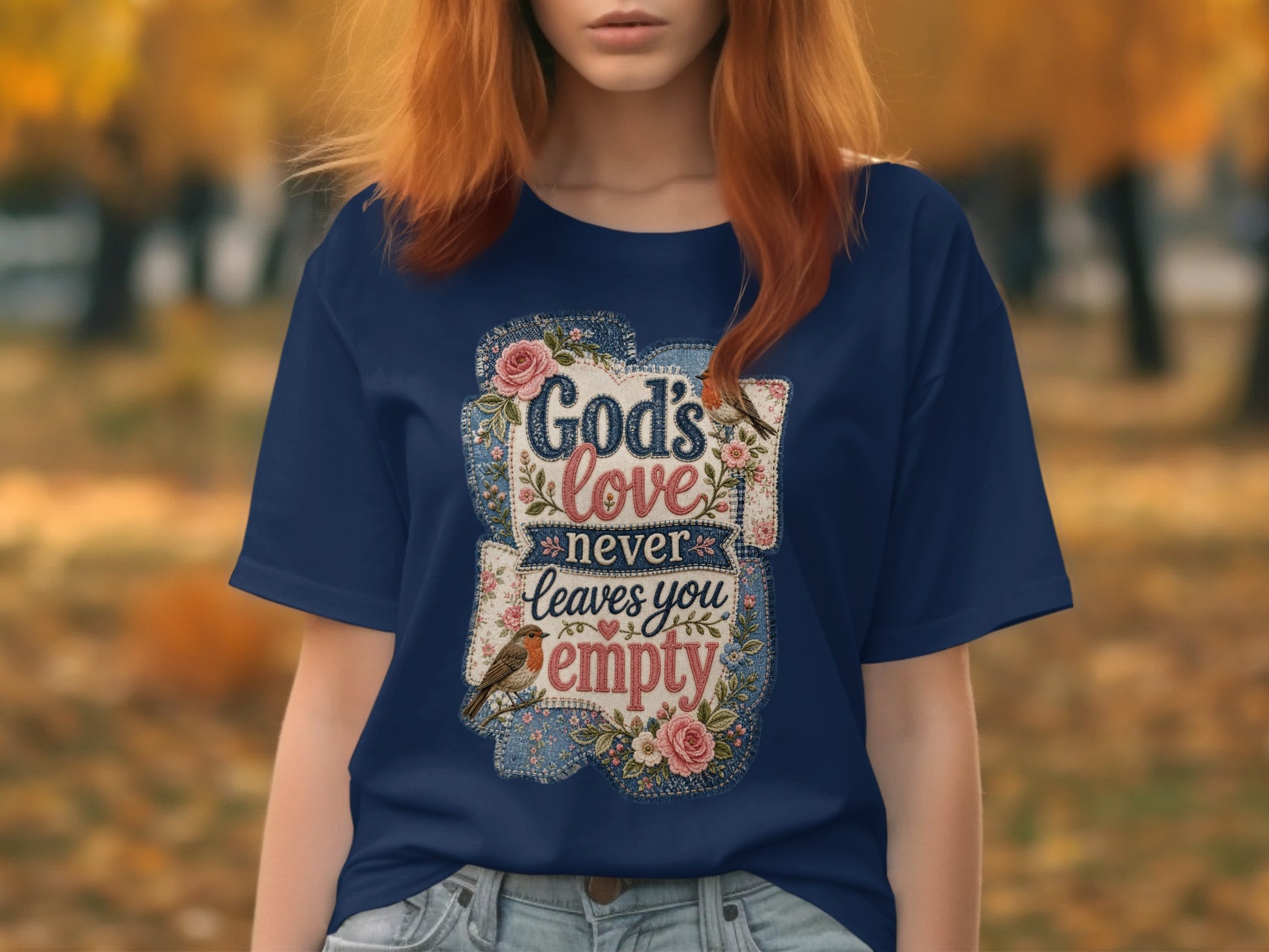 Dark blue t-shirt with floral and bird graphic and "God's love never leaves you empty" text.