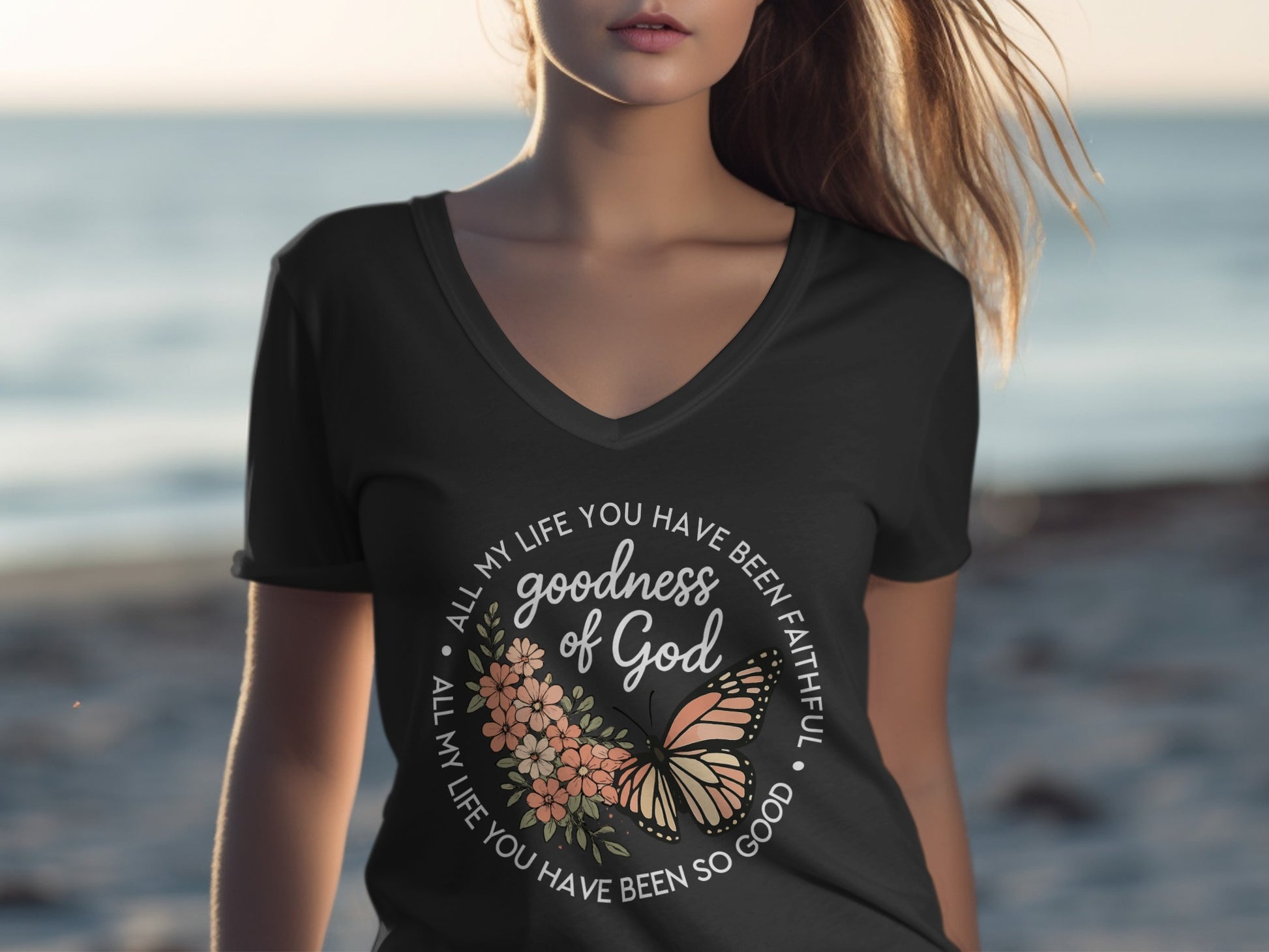 Woman wearing a v-neck t-shirt with floral and butterfly graphic and text.