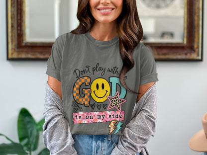 Graphic t-shirt with text "Don't play with God is on my side" and smiley face.