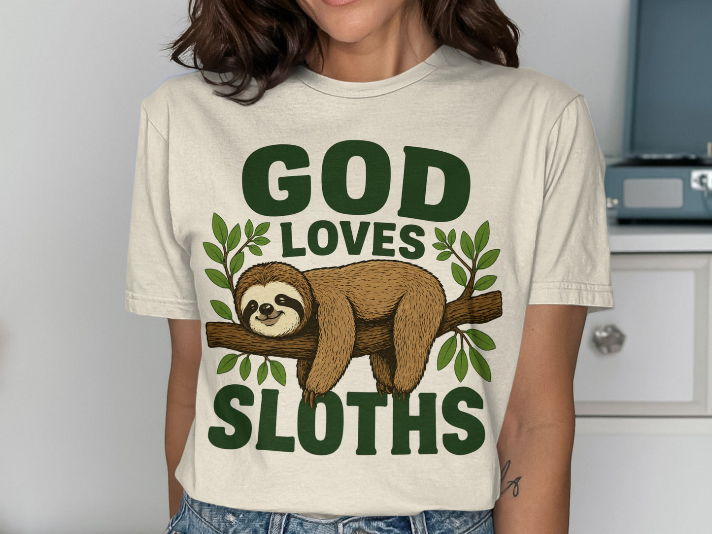 Cream t-shirt with "GOD LOVES SLOTHS" and a sloth on a branch.