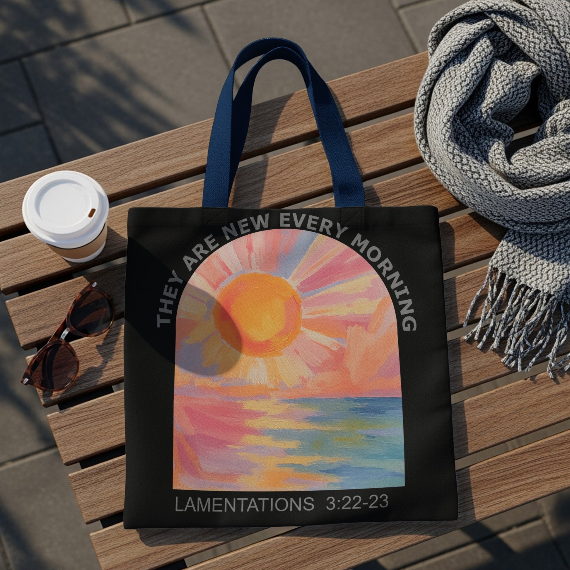 Black tote bag with sunrise over water art and "LAMENTATIONS 3:22-23" text.