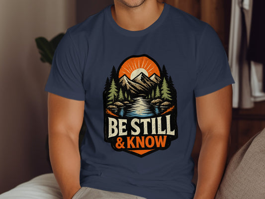 Navy t-shirt with mountains, sun, and "Be Still & Know" text.