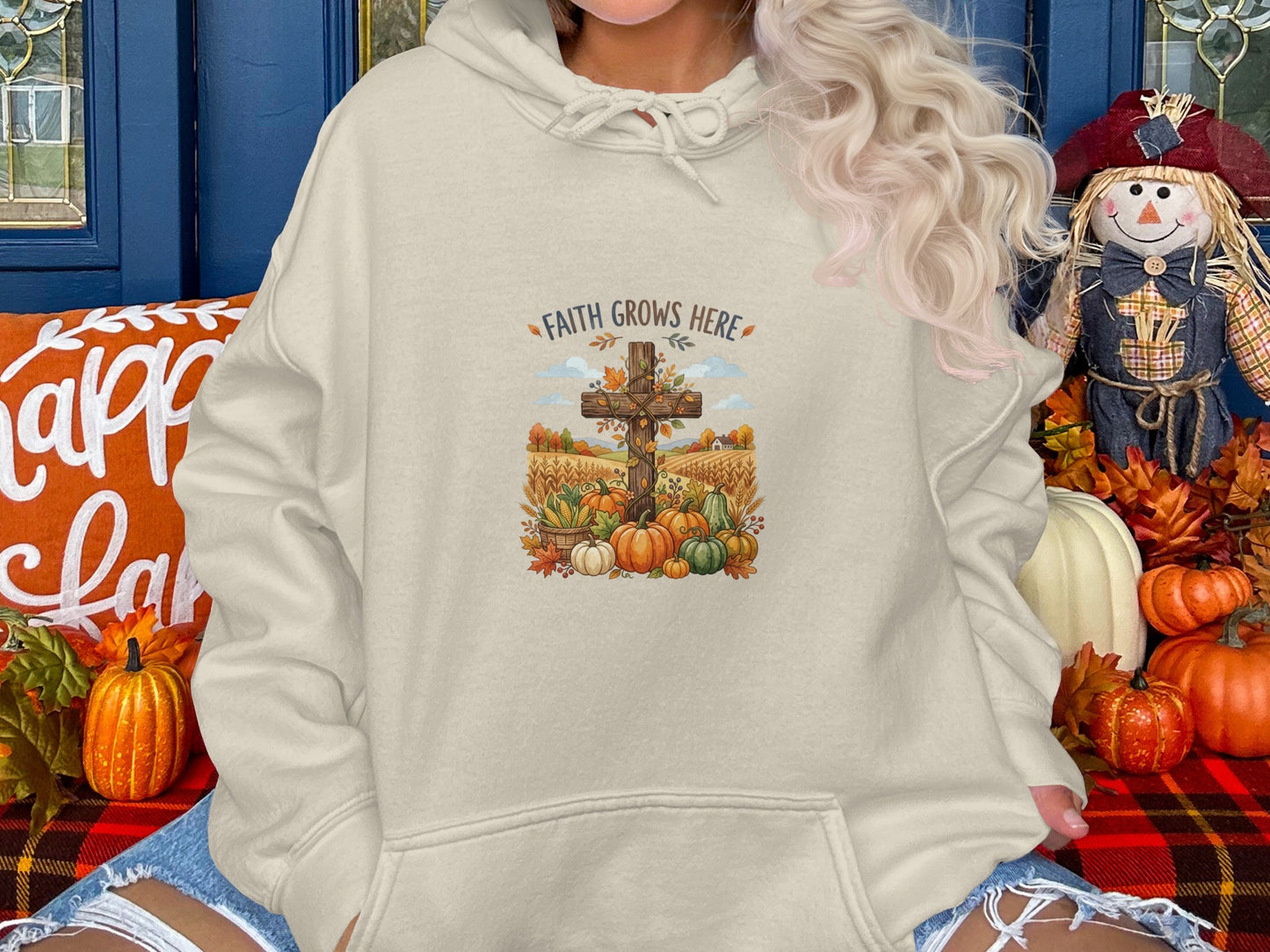 Cream hoodie with a graphic of a cross, pumpkins, and autumn foliage.