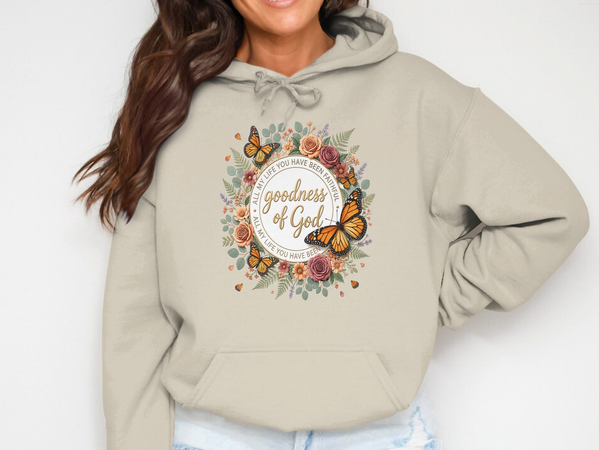 Beige hooded sweatshirt with floral wreath and "Goodness of God" text.
