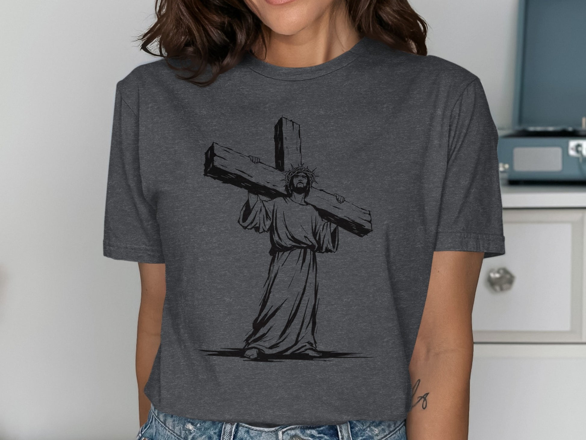 Jesus Christ carrying the cross in black silhouette on a grey t-shirt.