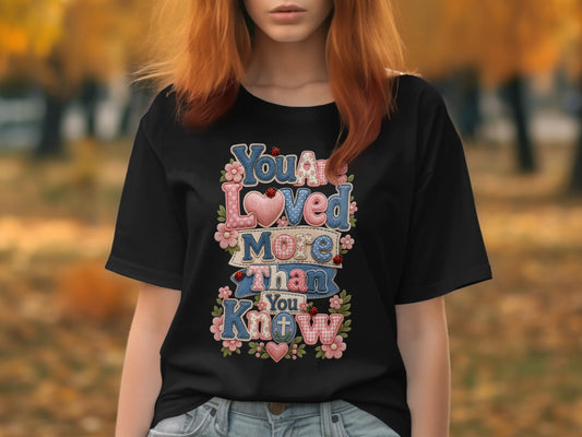 Black t-shirt with "You are loved more than you know" in colorful lettering.