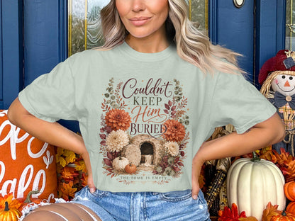 Light green t-shirt with "Couldn't Keep Him Buried" text and empty tomb graphic.