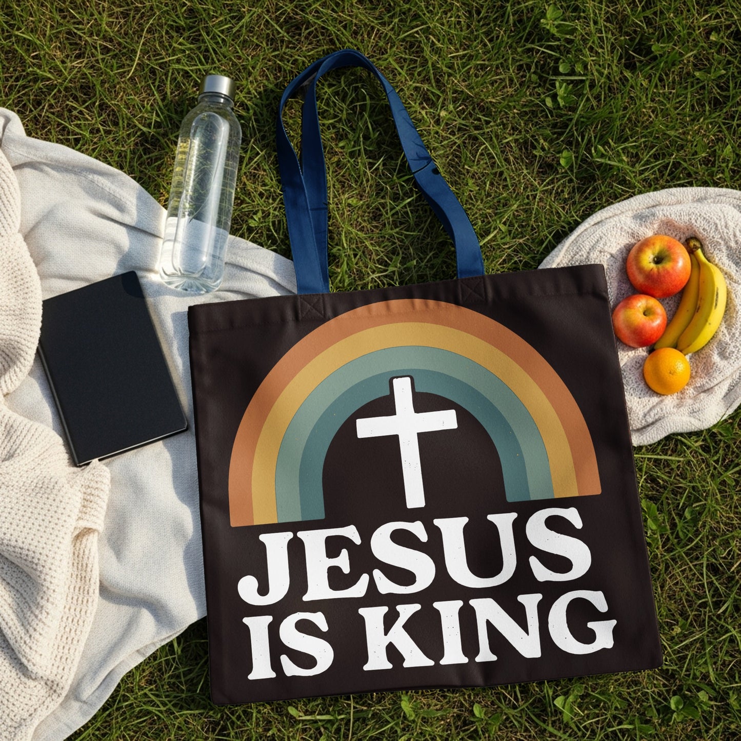 Black tote bag with "JESUS IS KING" text and rainbow cross graphic.