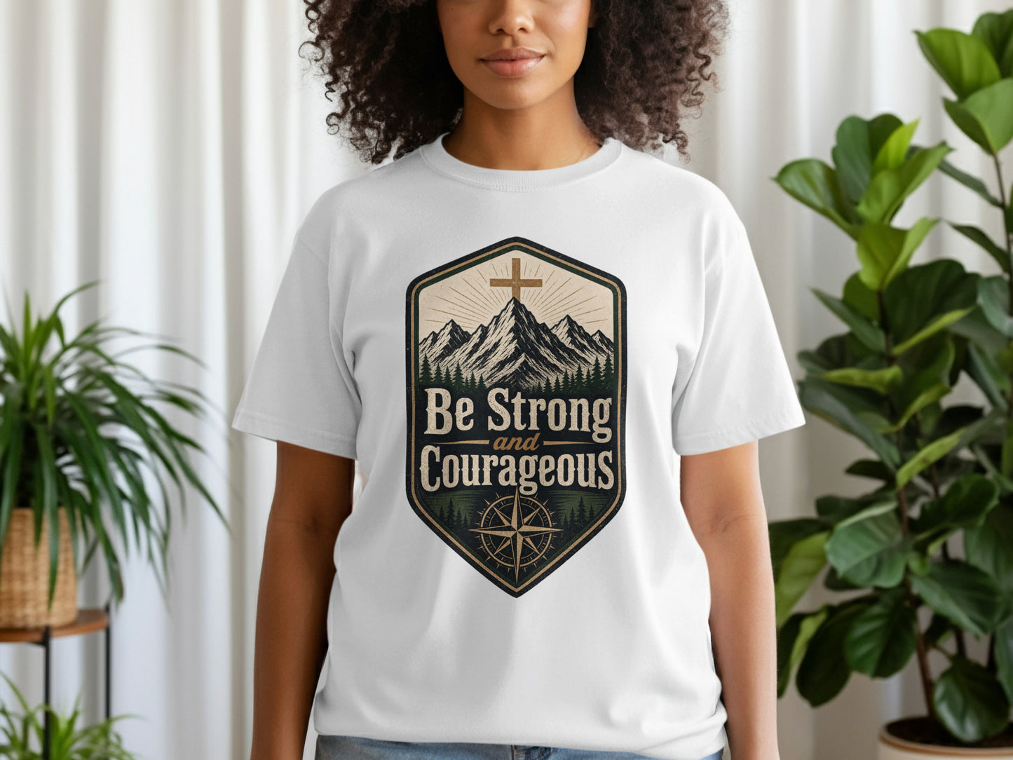 White t-shirt with "Be Strong and Courageous" text and mountain graphic.