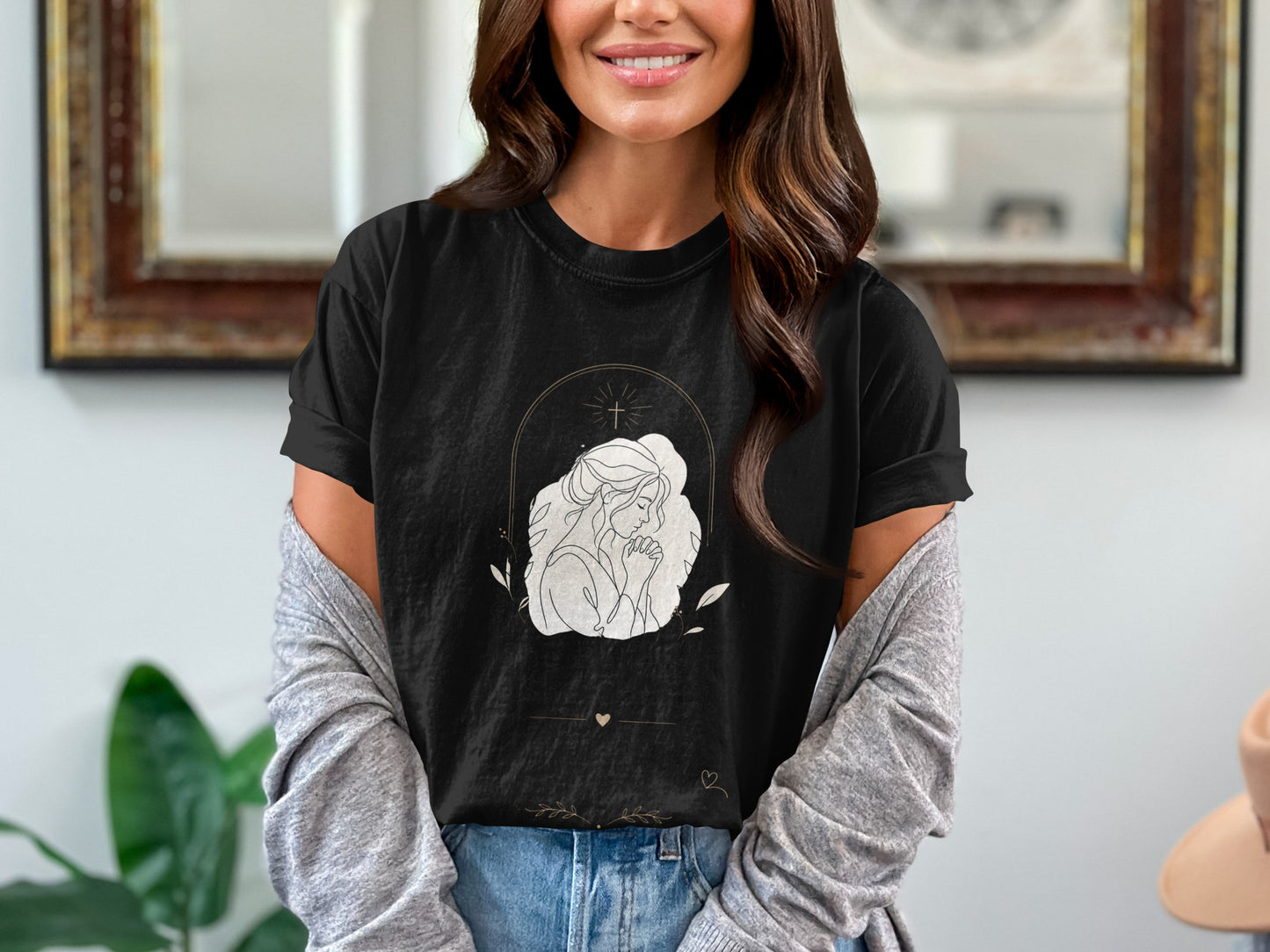 Black t-shirt with a white line art design of a woman praying with a cross above.