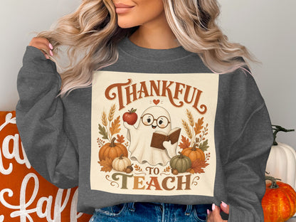 Ghost holding apple and book with text "Thankful to Teach" and pumpkins.