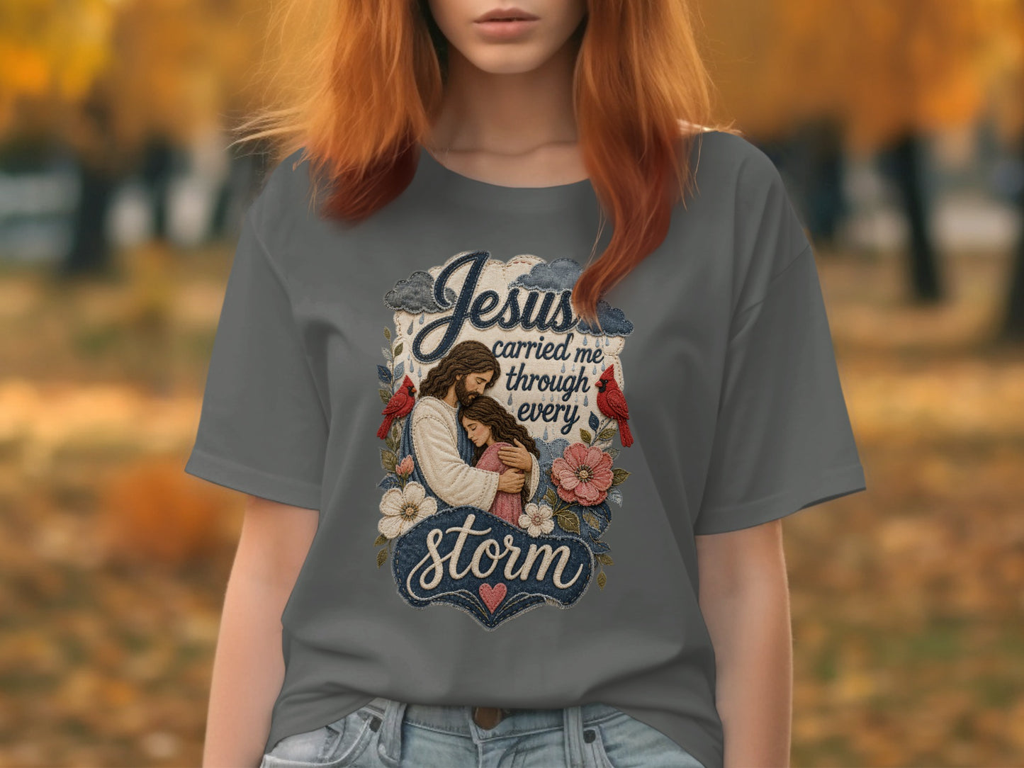 Jesus carried me through every storm graphic on a grey t-shirt.