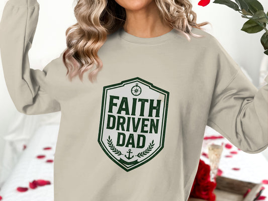 Beige sweatshirt with green shield graphic reading "FAITH DRIVEN DAD".
