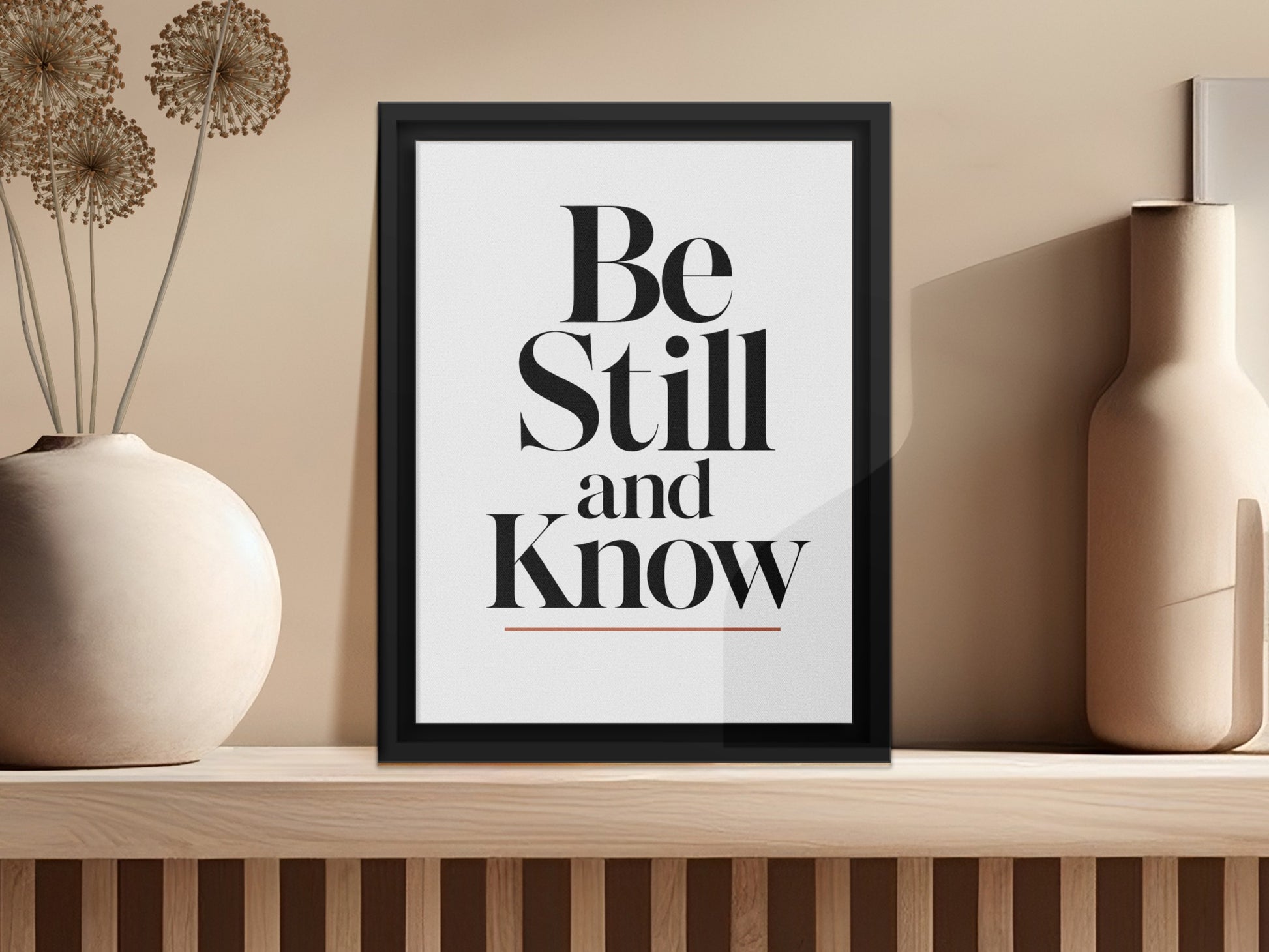 Framed artwork with "Be Still and Know" text, alongside decorative vases.