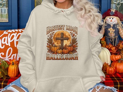 Beige hoodie with harvest moon, cross, pumpkins, and wheat graphic.