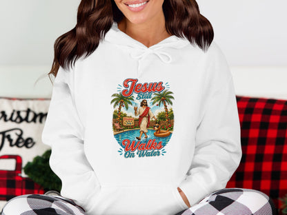 Hoodie with "Jesus Still Walks On Water" graphic and tropical scene.