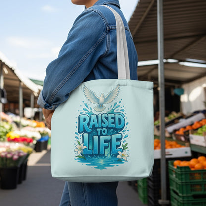 Light blue tote bag with a dove and "RAISED TO LIFE" text in blue lettering.