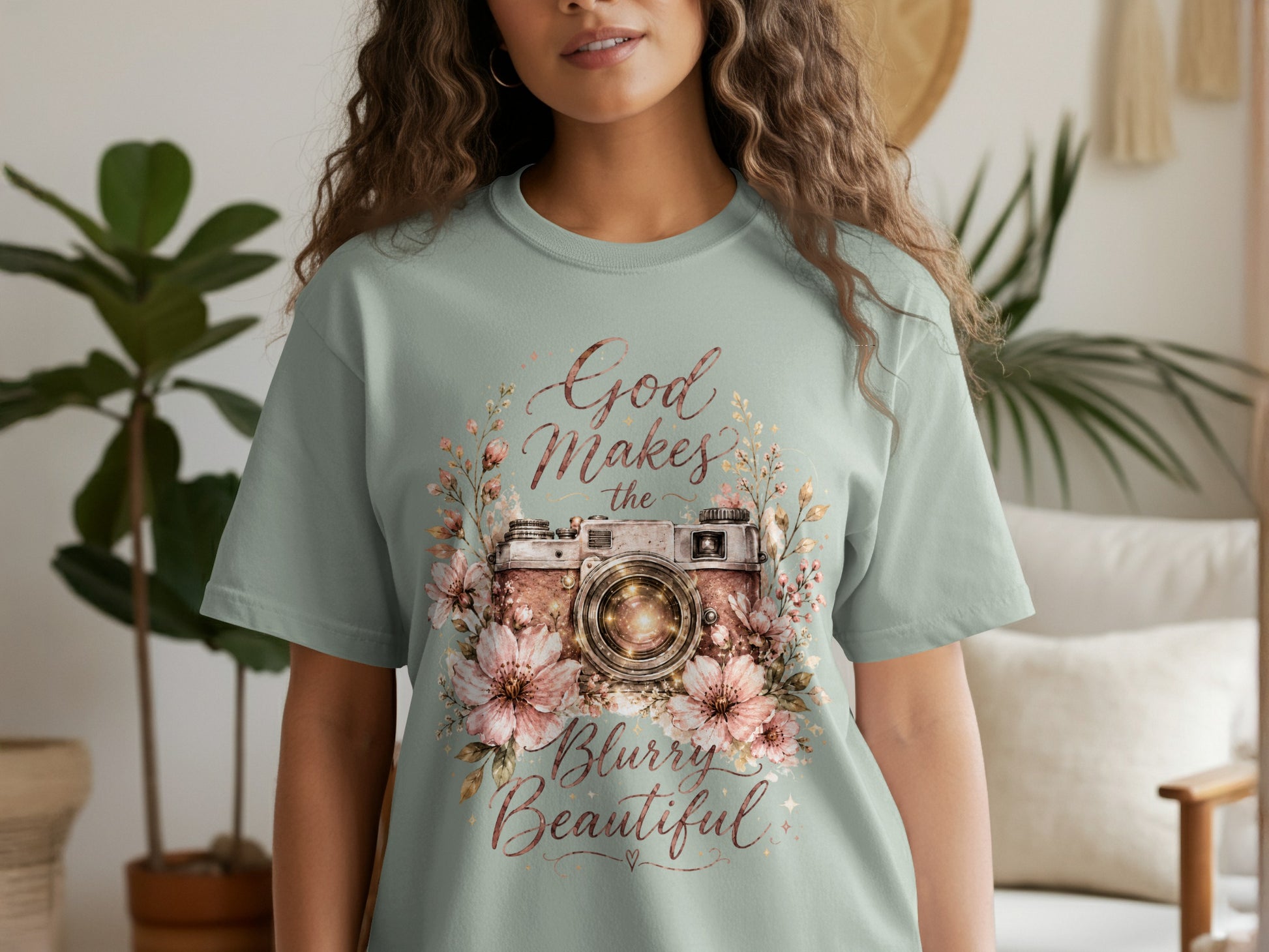 Light green t-shirt with a vintage camera surrounded by flowers and text "God Makes the Blurry Beautiful."