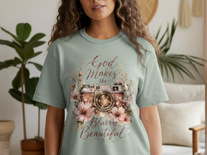 Light green t-shirt with a vintage camera surrounded by flowers and text "God Makes the Blurry Beautiful."