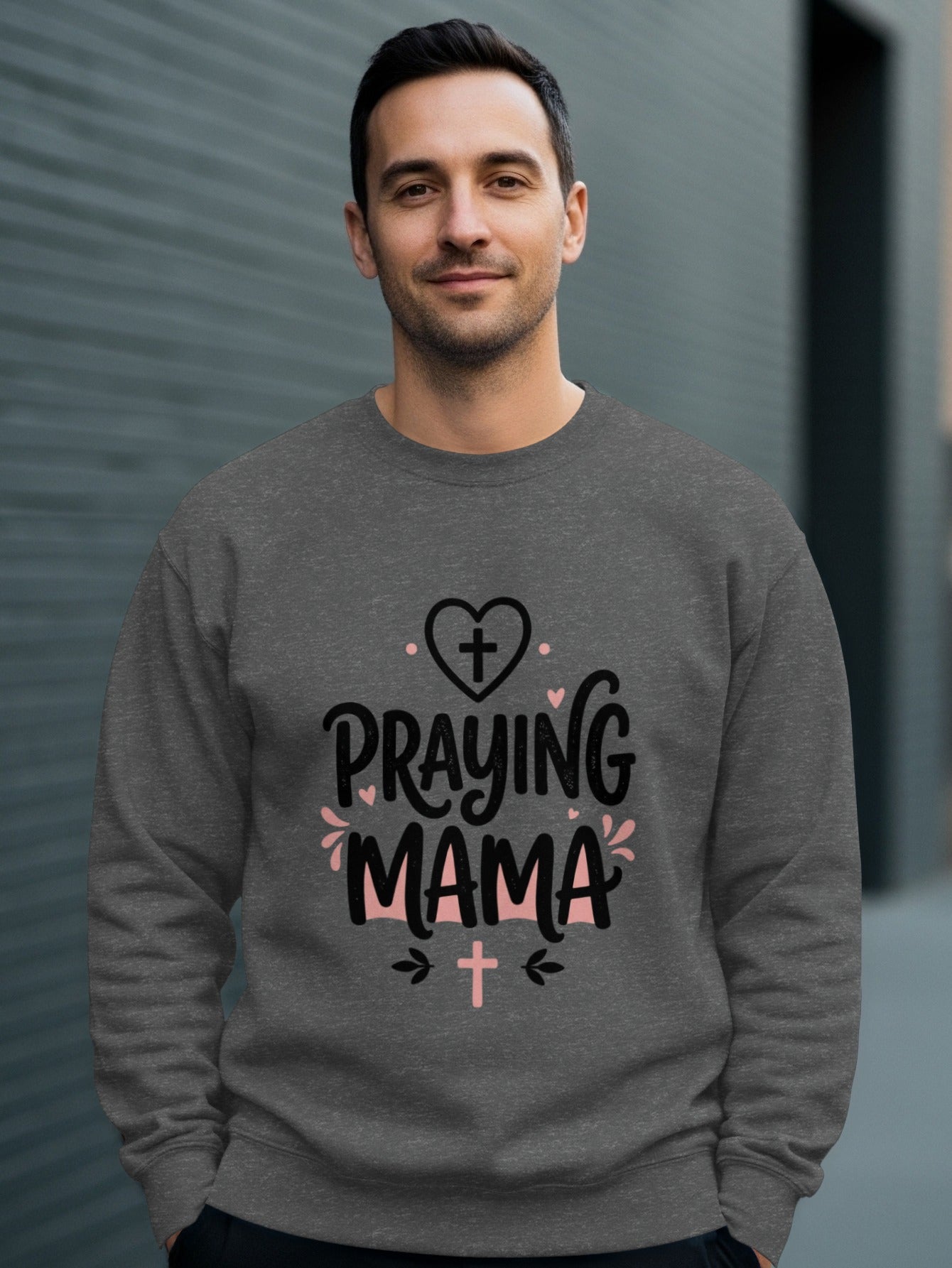 Man wearing gray sweatshirt with "Praying Mama" text and cross graphics.
