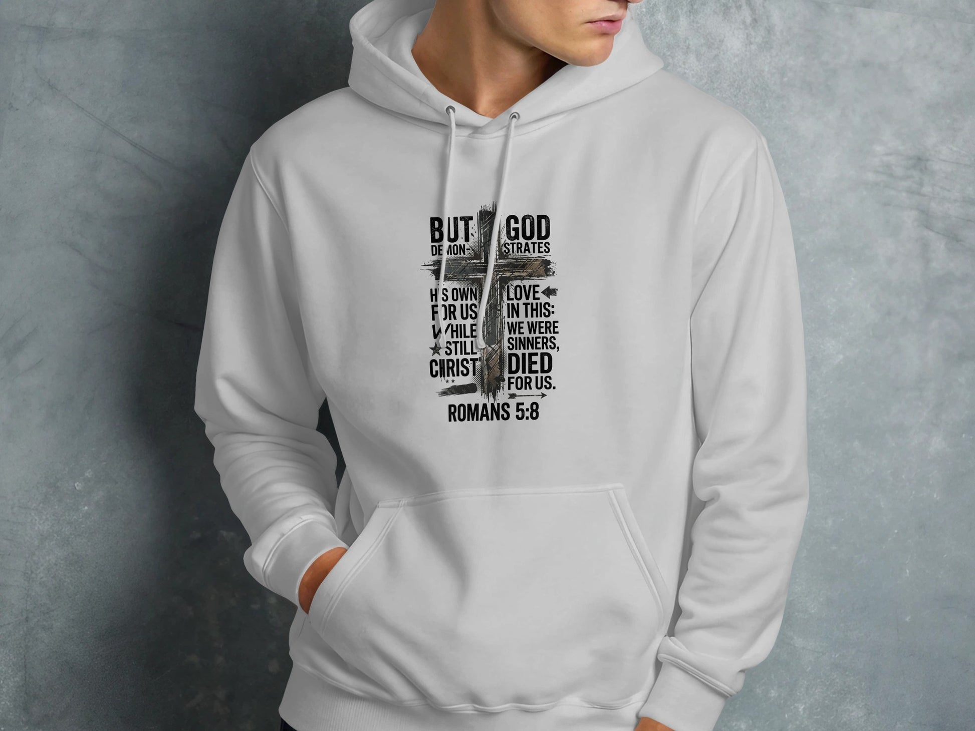 Hoodie with "But God Demonstrates His Own Love For Us In This: While We Were Still Sinners, Christ Died For Us. Romans 5:8" text.