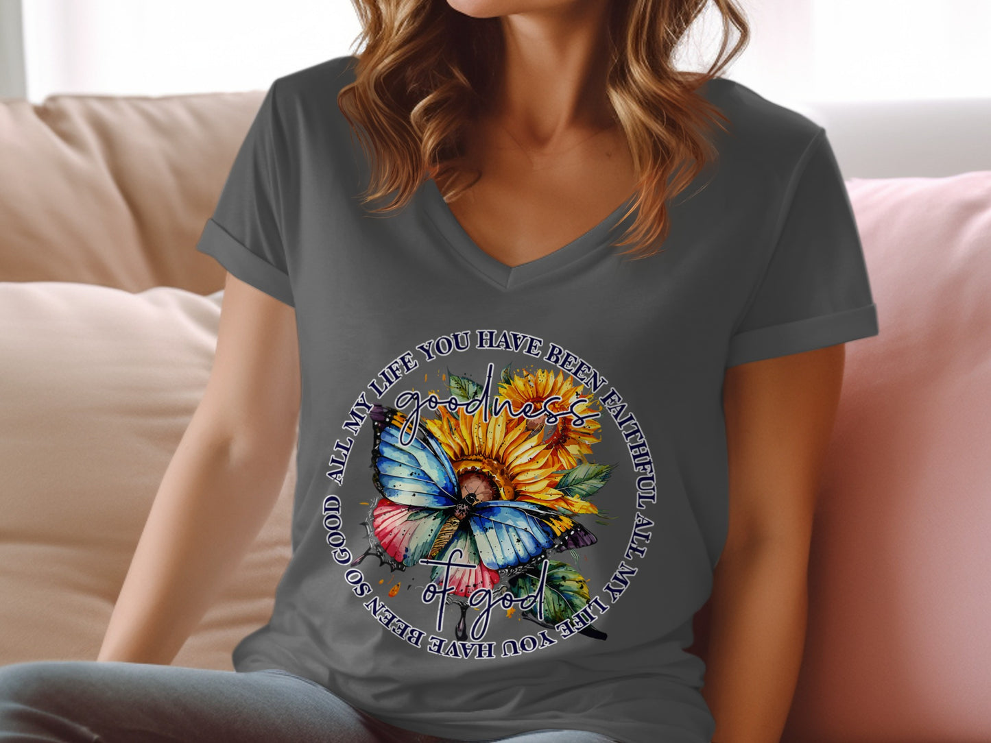 Woman wearing a gray v-neck t-shirt with a butterfly and sunflower graphic.